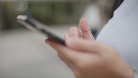 Frau-geht-die-Stadtstraße-mit-dem-Smartphone.-Nahaufnahme.-Kommunikation,-soziale-Netzwerke,-Online-Konzept.