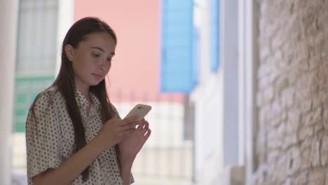 Frau-mit-Smartphone-in-der-Hand,-stehend-auf-der-Stadtstraße