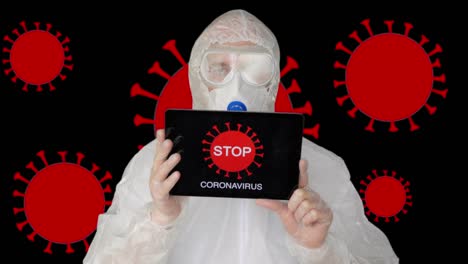 Bio-engineer-in-protective-suit-and-face-mask-showing-tablet-pc-with-sign-stop-corona-virus.-Man-in-protective-coat-and-mask-holding-tablet-with-microbe-molecules.-Covid-19-pandemia.