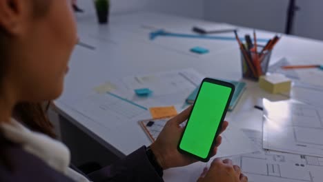 Business-woman-holding-smart-phone-green-screen-at-the-office