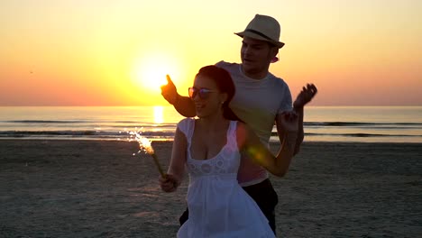 Paare-tanzen-mit-einem-Feuerwerk-Kerze-am-Strand-bei-Sonnenaufgang