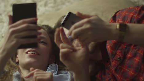 Young-Couple-are-Laying-on-the-Floor-and-Using-Mobile-Phones.-Casual-Lifestyle.