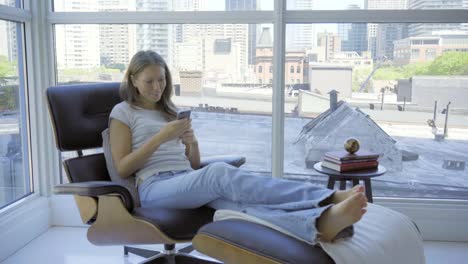 caucasian-woman-home-mobile-cell-phone-online-social-media-in-chair