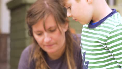 Niedliche-kleine-Junge-verzieren-Ostereier-mit-seiner-Familie-in-den-Ferien