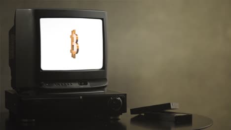 Vintage-TV-auf-Holztisch-mit-Bitcoin.-Alte-TV-zeigt-Bitcoin.-In-der-Nähe-des-Fernsehers-gibt-es-Filmkassetten-und-video-player