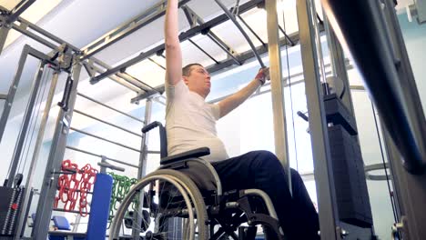 Training-process-of-a-disabled-man-in-a-wheelchair-with-a-weight-lifting-mechanism