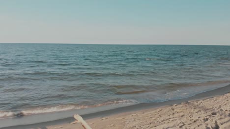 Drone-bewegt-sich-hinter-Frau-in-Sport-Wear-hält-Yoga-Asana-Position-am-Meer-oder-Ozean-Sandstrand.-Windige-sonniges-Wetter.-Luftaufnahme-des-friedlichen-Gesundheit-Mädchen-Praxis-durchführen