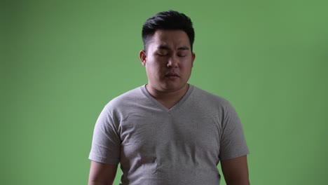 Young-handsome-overweight-Asian-man-against-green-background