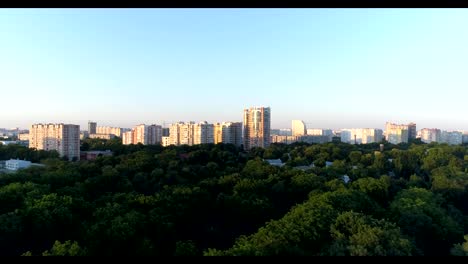 Aerial---City-park,-green-trees-and-tall-buildings.