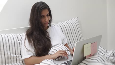 young-and-pretty-woman-is-typing-text-on-laptop-lying-on-the-bed-in-her-room