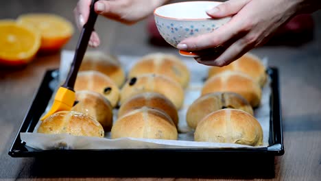 Hot-Cross-Buns-auf-Backblech.-Weibliche-Hände-mit-Sirup-bedecken.