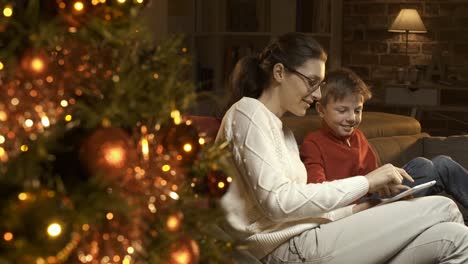 Niño-y-su-madre-utilizando-una-tableta-digital-juntos-en-Navidad