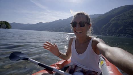 Joven-tomando-retratos-selfie-en-canoa-roja-montaña-lago-una-mujer-disfruta-vacaciones-de-verano-tener-diversión-en-actividades-al-aire-libre---lenta