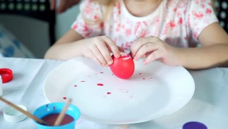 Kleines-Mädchen-versucht,-buntes-Ostereier-zu-schälen