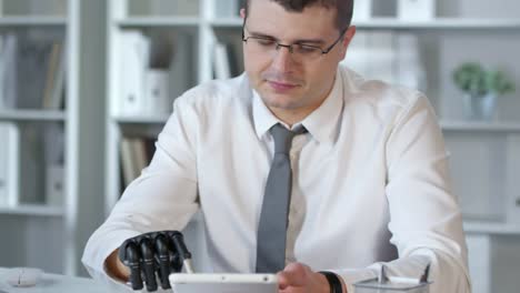 Hombre-de-negocios-con-brazo-protésico-usando-Tablet-en-Office