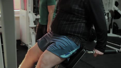 Cheerful-fat-man-performs-a-wrong-exercise-in-the-gym.-For-the-first-time-in-a-fitness-club