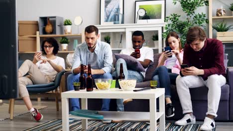 Grupo-de-jóvenes-que-utilizan-teléfonos-inteligentes-tocando-la-pantalla-en-casa-juntos