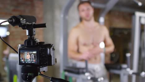 Shirtless-Man-Showing-Leg-Raises-on-Parallel-Bars-on-Camera