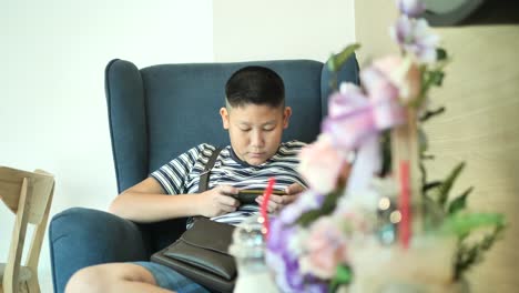 Young-teenager-playing-game-on-smartphone-in-cafe