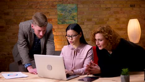 Closeup-Shooting-von-jungen-asiatischen-Geschäftsfrauen,-die-am-Laptop-arbeiten-und-den-Erfolg-mit-zwei-Kollegen-feiern.-Mitarbeiterinnen-mit-Tablet