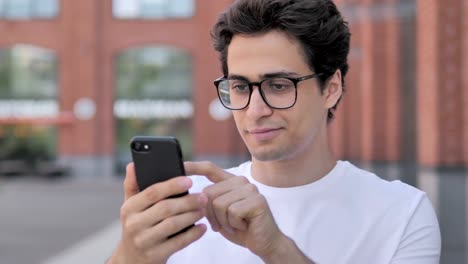 Outdoor-Portrait-of-Young-Man-Using-Smartphone