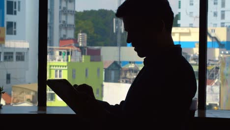 Mann-mit-Tablet-am-Fenster