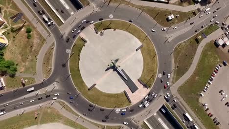 cars-are-moving-on-round-intersection-in-city-in-summer-day,-aerial-shot