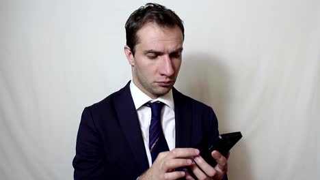 Young-handsome-businessman-pulls-out-his-smartphone-from-his-pocket-and-looks-through-the-news-feed.