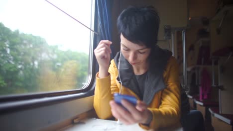 chica-utiliza-auriculares-en-el-tren-por-la-ventana