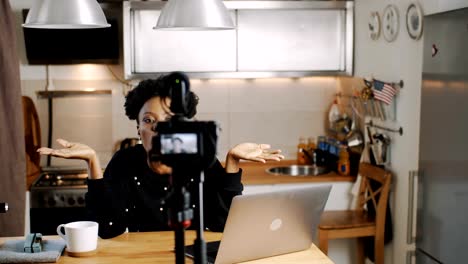 Happy-young-beautiful-black-lifestyle-blogger-woman-making-new-entertainment-video-with-camera-at-home-slow-motion.