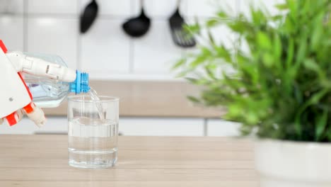 Robotic-prosthetic-hand-is-pouring-water-in-glass-from-the-bottle-in-the-kitchen