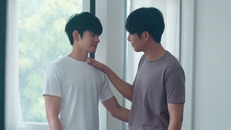 Asian-Gay-couple-standing-and-hugging-near-the-window-at-home.-Young-Asian-LGBTQ+-men-kissing-happy-relax-rest-together-spend-romantic-time-in-living-room-at-modern-house-in-the-morning-concept.