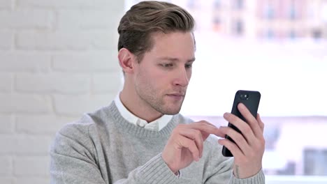 The-Portrait-of-Relaxed-Creative-Young-Man-using-Smartphone