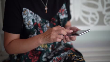 Senior-asiatische-Frau-mit-Dem-Smartphone-zu-Hause