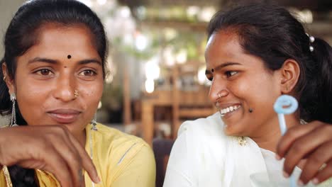 Two-women-chilling-sipping-drinks-using-technology-in-cafe