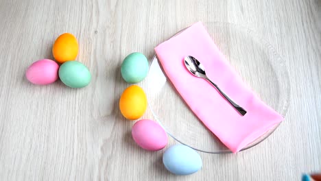 Hand-takes-a-teaspoon-from-the-table.-On-the-table-are-colored-easter-eggs.