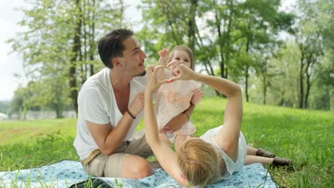 CLOSE-UP:-Young-family-with-cheerful-baby-making-heart-with-hands-and-waving