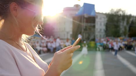 glückliche-Frau-hält-android-stehen-in-der-Innenstadt,-Frauen-sitzen-auf-mobiles-Internet-im-Freien,-junge-Frau