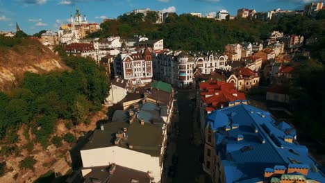 Zángano-de-la-cámara-se-mueve-bajo-techos-de-edificios-en-antigua-europeas-callejuelas-con-casas-de-colores-y-los-peatones-al-atardecer-4K