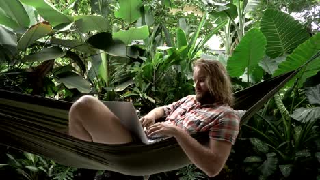 Сryptocurrency-trader-making-bargain-on-laptop-while-lying-on-hammock