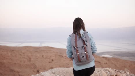 Frau-nimmt-Fotos-von-Montain-Landschaft.-Slow-Motion.-Lässige-Reisenden-Mädchen-mit-Rucksack-mit-Smartphone.-Israel-Totes-Meer