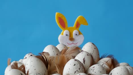 Easter-bunny-is-hiding-behind-the-eggs-on-blue-background.