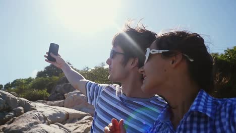 Young-couple-taking-selfie-portrait-by-beautiful-mountain-with-lense-flare-effects-and-the-sun-on-background-in-slow-motion.-1920x1080