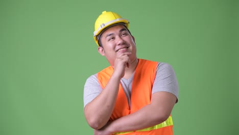 Trabajador-de-la-construcción-del-joven-guapo-asiáticos-con-sobrepeso-sobre-fondo-verde