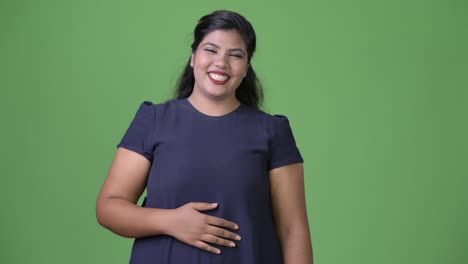 Young-overweight-beautiful-Indian-businesswoman-against-green-background