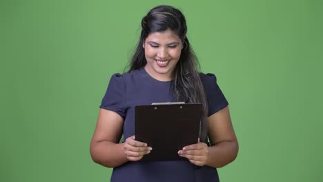 Young-overweight-beautiful-Indian-businesswoman-against-green-background