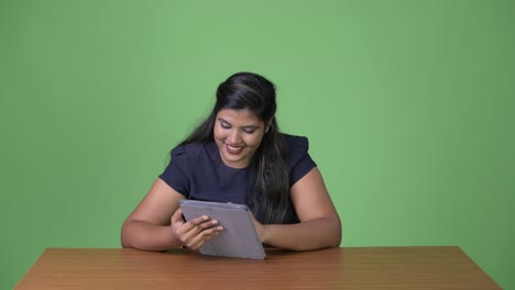 Young-overweight-beautiful-Indian-businesswoman-against-green-background