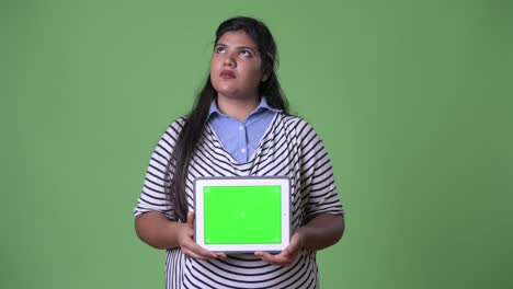 Young-overweight-beautiful-Indian-businesswoman-against-green-background