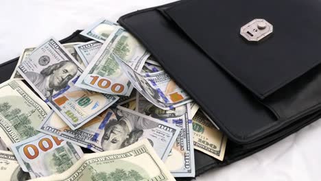 black-money-bag-full-of-dollars,-bags-and-many-100-usd-banknotes,