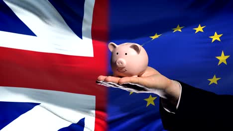 Großbritannien-Investitionen-in-die-EU-Hand,-Geld-im-Sparschwein,-Flagge-Hintergrund